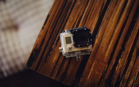 A GoPro in a dive housing with a red filter and video light on a tray, filming a coral reef