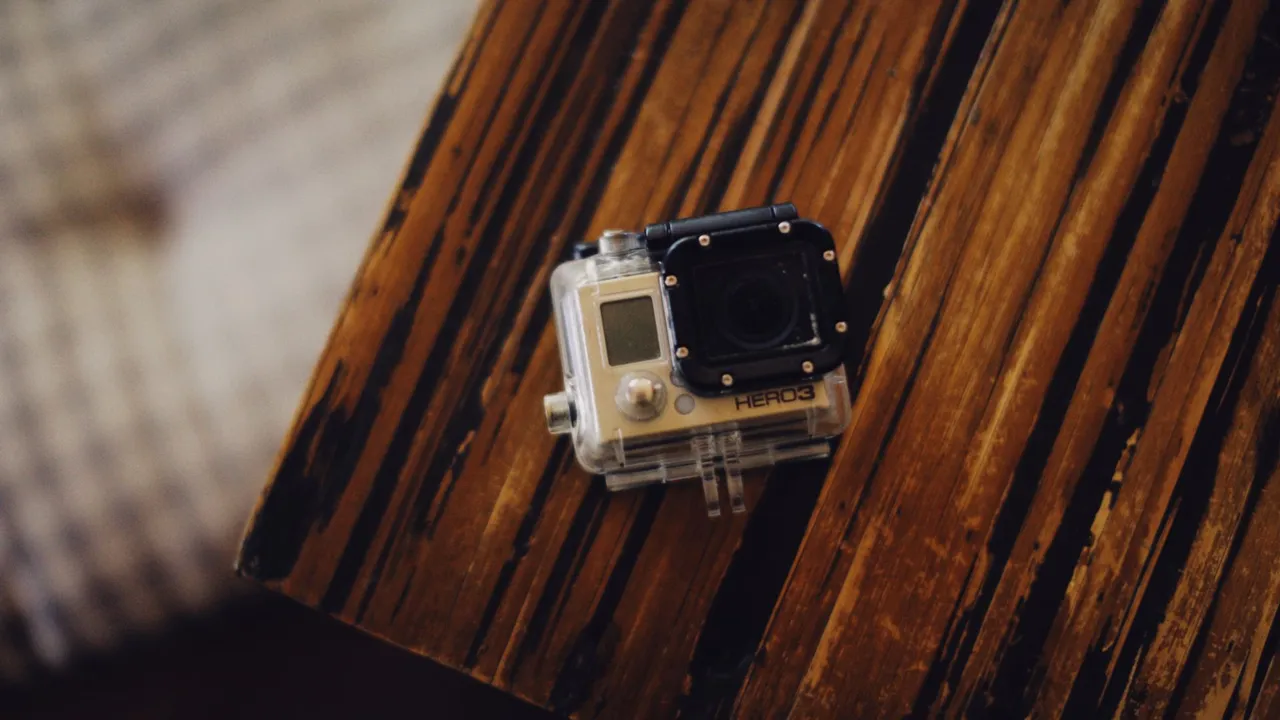 A GoPro in a dive housing with a red filter and video light on a tray, filming a coral reef